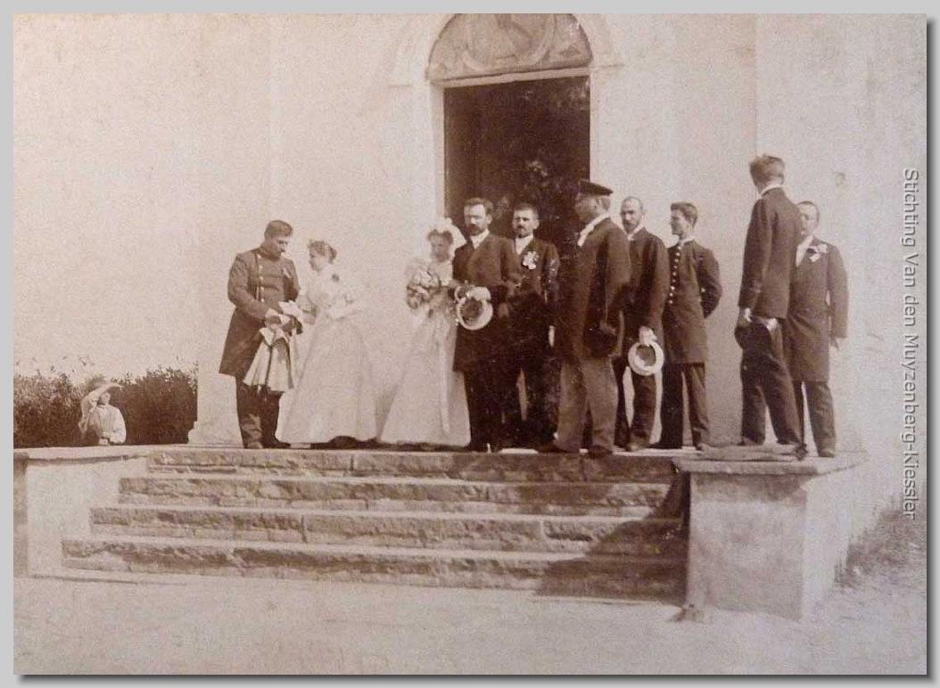 Bruidspaar met meerdere mannen (sommigen in uniform) en een dame voor de ingang van een kerk