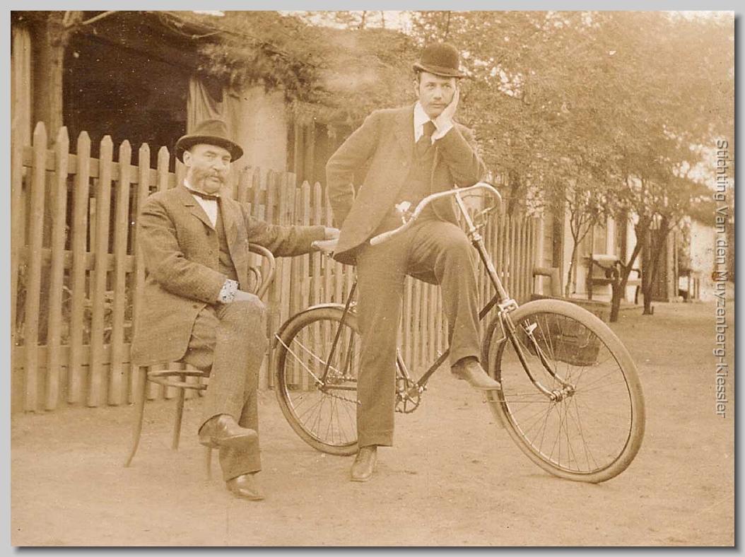 Een man zittend op een stoel en de andere op het zadel van een fiets