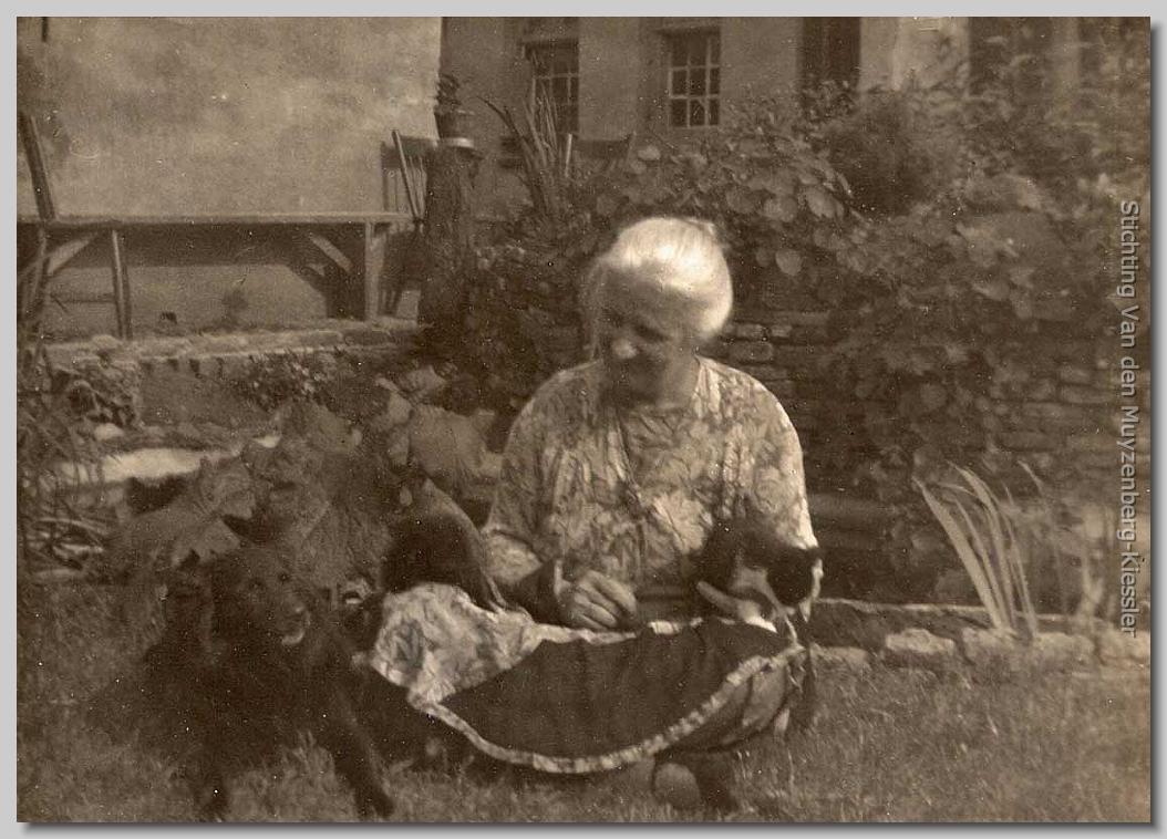 dame  zittend op de grond met twee poezen en een hond