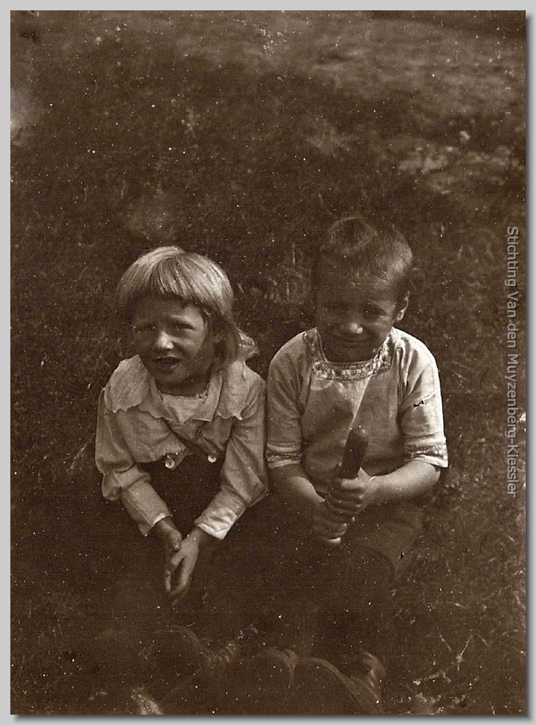 twee jongetjes zittend in het gras opkijkend naar de kamera