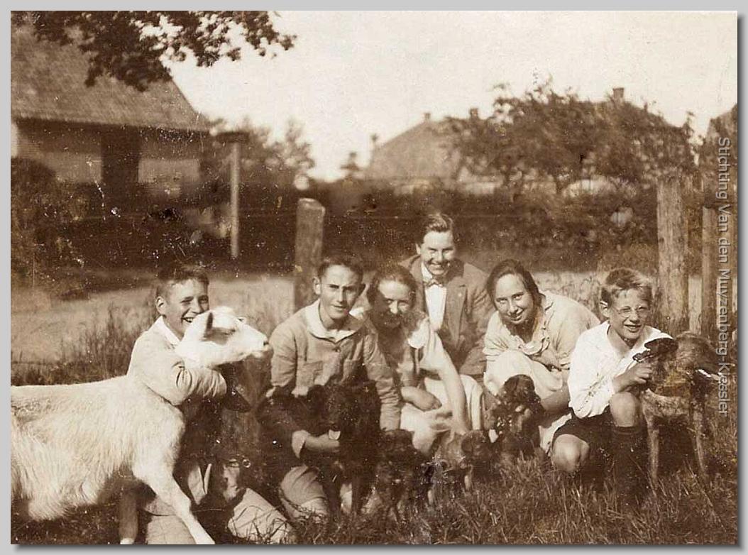 zes jongeren, drie honden en een geit zittend op het gras