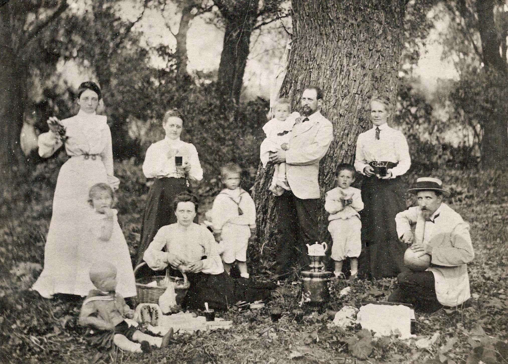 Groep mensen en kinderen in het bos bij een grote boom . De samovar staat tussen de bladeren