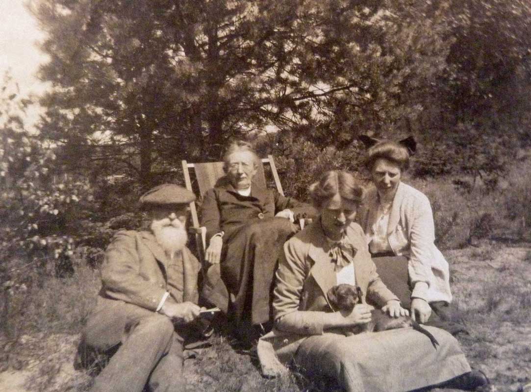 Vier mensen met een hond in een tuin met bomen