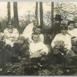 Gezin, 1912 Foto genomen in de natuur. Allen zittend op de grond bij kale bomen