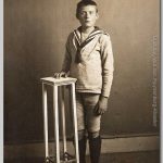 Dick, 1915 Jongen met padvinderssjaal naast een hoog tafeltje