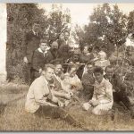 Gezin, 1922/1924 Een groep mensen op het gras rondom een tafeltje met de samovar en bomen op de achtergrond