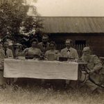 Groep mensen achter en naast een tafel met een grote samovar