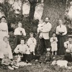 Groep mensen en kinderen in het bos bij een grote boom . De samovar staat tussen de bladeren