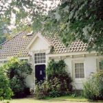 de ingang van het huis met grote bomen er om heen