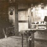 Deur met lepelrekje er naast en dienblad met theeservies op een kleine tafel.