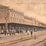 Aleksandrów - Station - spoorkant Heel lang gebouw met drie sporen er voor, mensen op het perron en op de rails