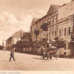 brede straat met telegraaf palen links, paard en wgen en overstekende man