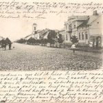 Brede kobbel straat met huizen er langs en lopende mensen