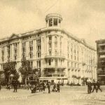 Half rond wit hoek gebouw met veel mensen op de straat