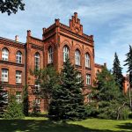 rood bakstenen gebouw met dennebomen er voor