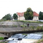 betonnen dijken, rivier en bisschopspaleis op de achtergrond