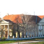 groot gebouw met aan ttwee kanten zuilen en hek er om heen
